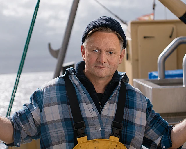 Mann auf Fischkutter mit Wollmütze