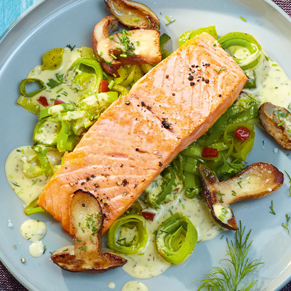 Lachs­filet mit Kräuter­senf­sauce, Lauch und Stein­pilzen